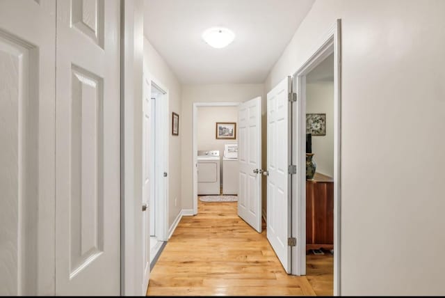 hall featuring light wood finished floors, baseboards, and separate washer and dryer