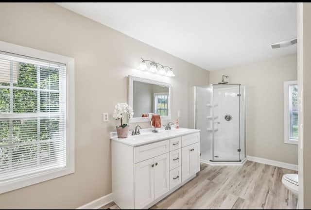 full bathroom with double vanity, baseboards, visible vents, wood finished floors, and a shower stall