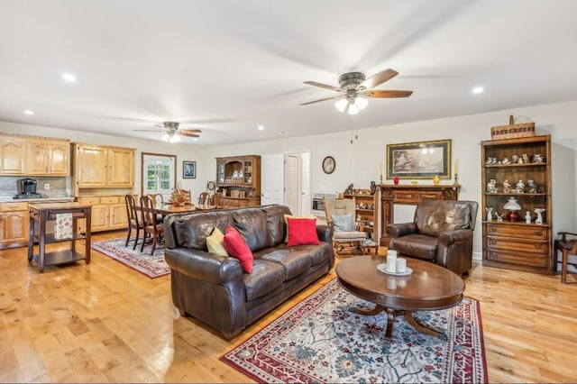 living room featuring light wood finished floors, a ceiling fan, and recessed lighting