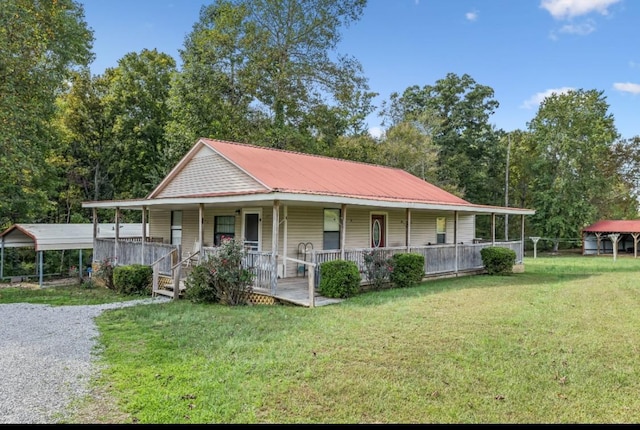 country-style home with gravel driveway, covered porch, a front yard, metal roof, and a carport