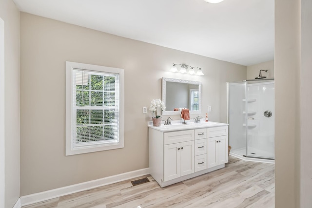 full bathroom with a sink, wood finished floors, baseboards, a shower stall, and double vanity