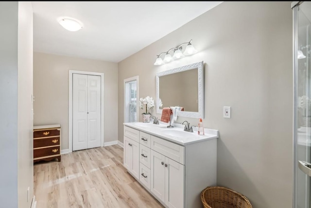 bathroom with double vanity, a sink, baseboards, and wood finished floors