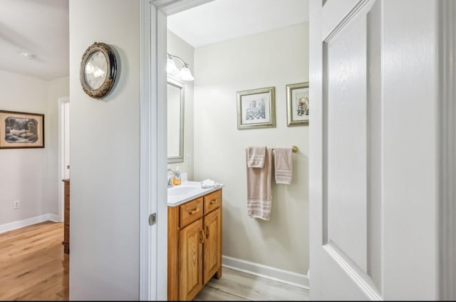 bathroom with baseboards, wood finished floors, and vanity