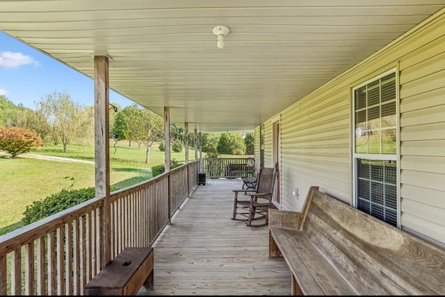 wooden deck featuring covered porch and a yard