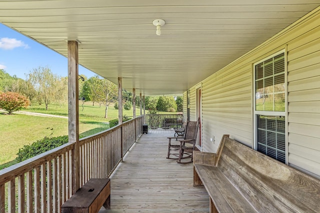 wooden deck featuring covered porch and a lawn