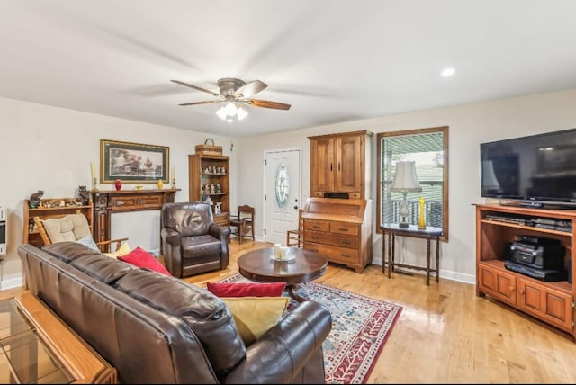 living area featuring baseboards, ceiling fan, and light wood-style floors