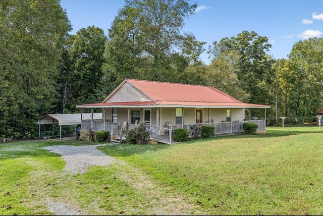 view of front of property with a detached carport, covered porch, a front yard, metal roof, and driveway