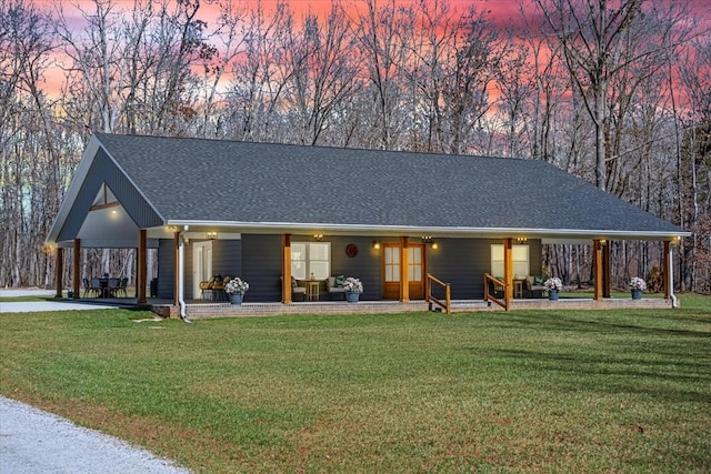 view of front of home with an attached carport, covered porch, roof with shingles, and a front lawn