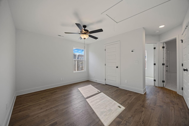 unfurnished bedroom featuring dark wood-style floors, visible vents, attic access, and baseboards