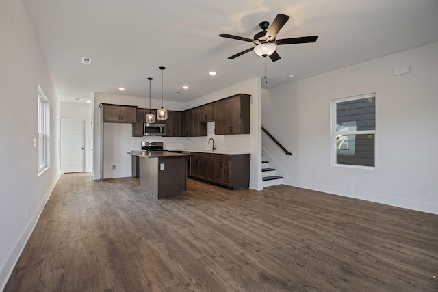 kitchen featuring dark wood-style flooring, appliances with stainless steel finishes, open floor plan, and a sink