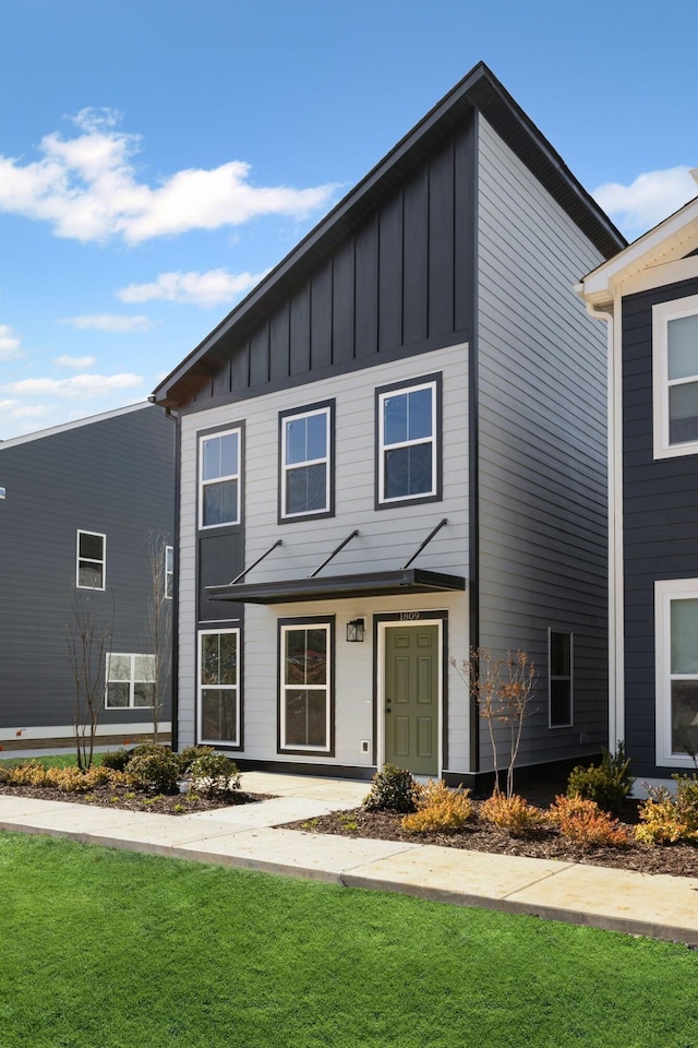 view of front facade with board and batten siding and a front lawn