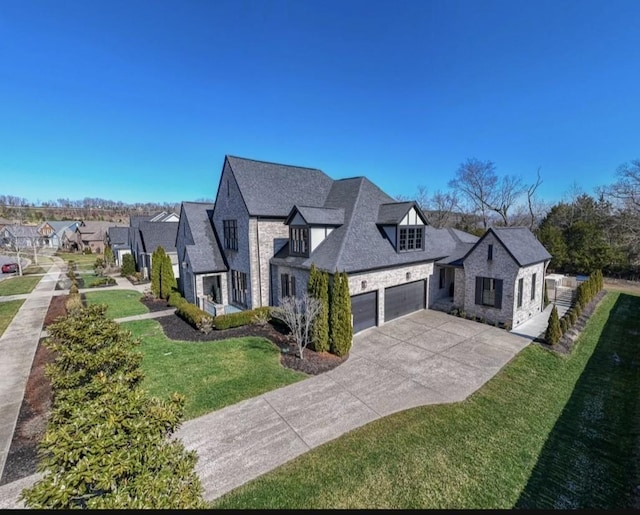 french country home with a garage, stone siding, concrete driveway, and a front yard