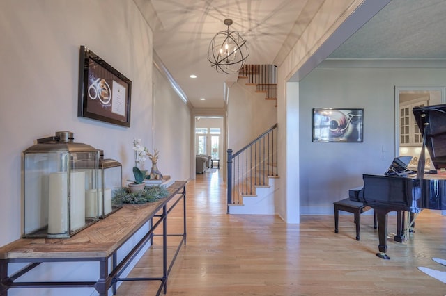 hallway featuring ornamental molding, wood finished floors, a chandelier, baseboards, and stairs