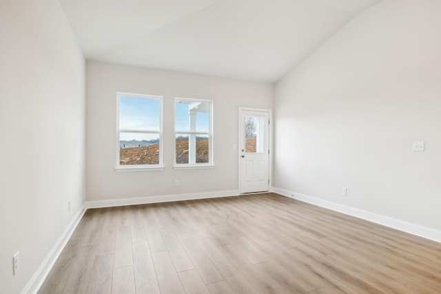 spare room with vaulted ceiling, baseboards, and wood finished floors