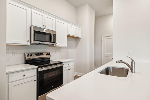 kitchen with a sink, white cabinets, light countertops, appliances with stainless steel finishes, and backsplash