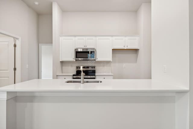 kitchen featuring light countertops, appliances with stainless steel finishes, backsplash, and white cabinets