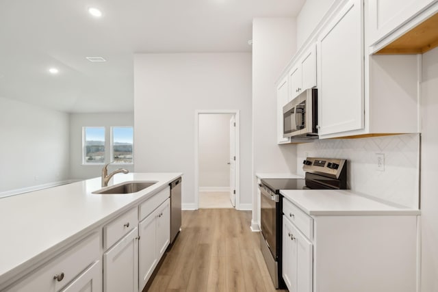 kitchen with appliances with stainless steel finishes, light countertops, a sink, and backsplash