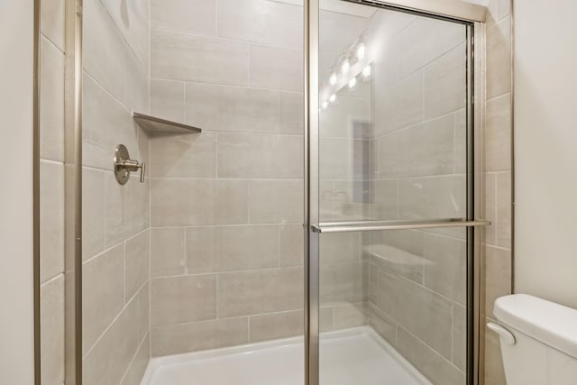 full bathroom featuring a stall shower and toilet