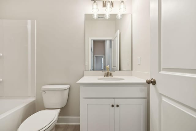 bathroom featuring baseboards, vanity, toilet, and bathing tub / shower combination