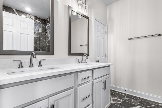 full bathroom with marble finish floor, a sink, baseboards, and double vanity