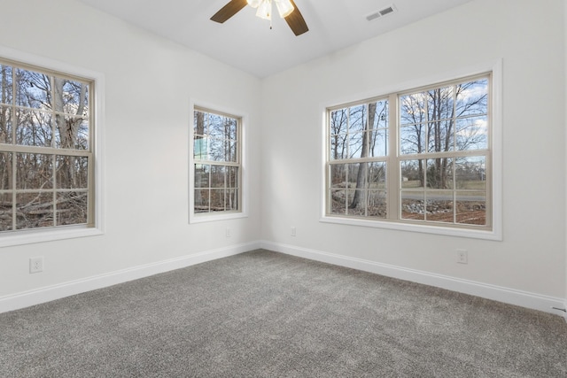 carpeted empty room with baseboards, visible vents, and a ceiling fan