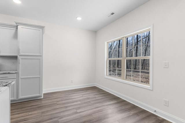 unfurnished dining area featuring recessed lighting, wood finished floors, visible vents, and baseboards