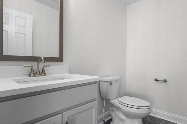 bathroom with toilet, baseboards, and vanity