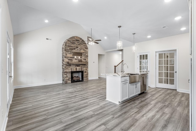 kitchen featuring a fireplace, a ceiling fan, open floor plan, a sink, and dishwasher