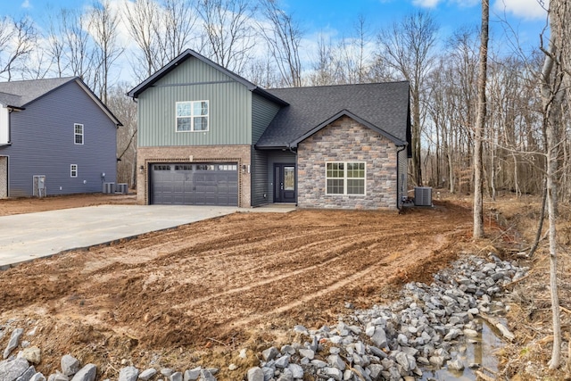 view of front of house featuring a garage, concrete driveway, a shingled roof, and central AC unit