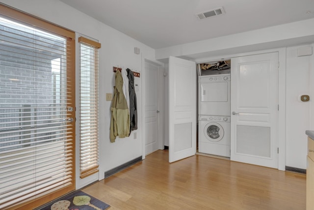 laundry area with stacked washer and dryer, laundry area, visible vents, and light wood-style flooring