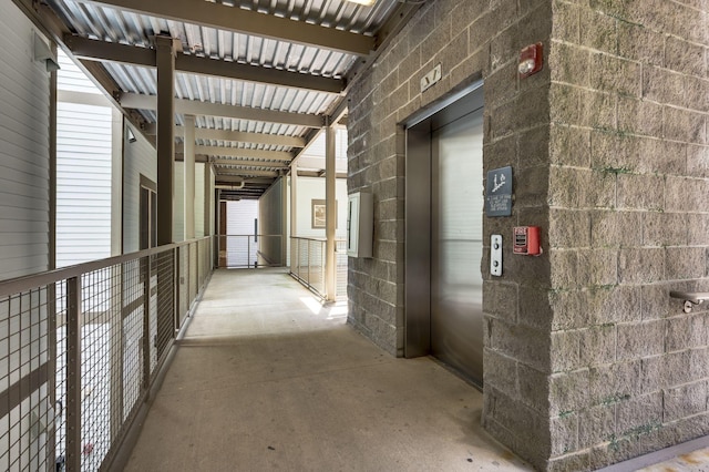 hallway with elevator and concrete floors