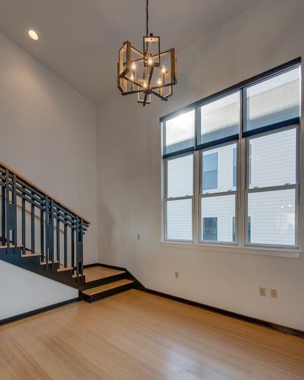 interior space featuring a notable chandelier, stairway, baseboards, and wood finished floors