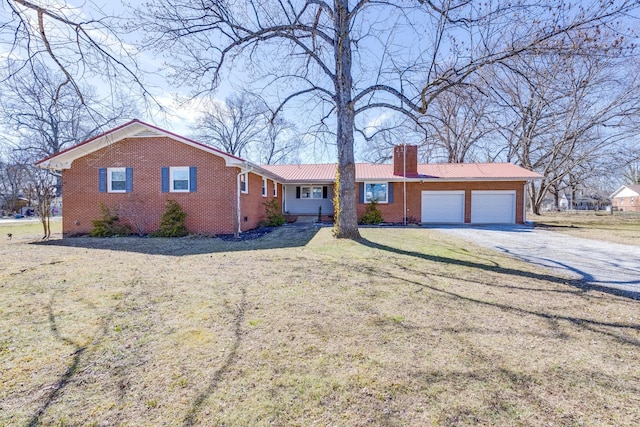 ranch-style home with a garage, a chimney, metal roof, gravel driveway, and brick siding