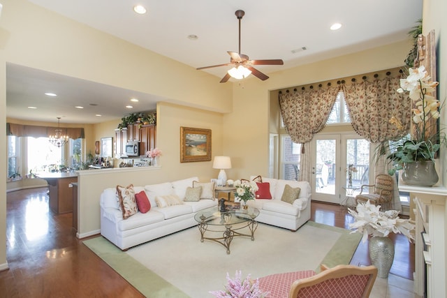 living area featuring ceiling fan with notable chandelier, recessed lighting, visible vents, and wood finished floors