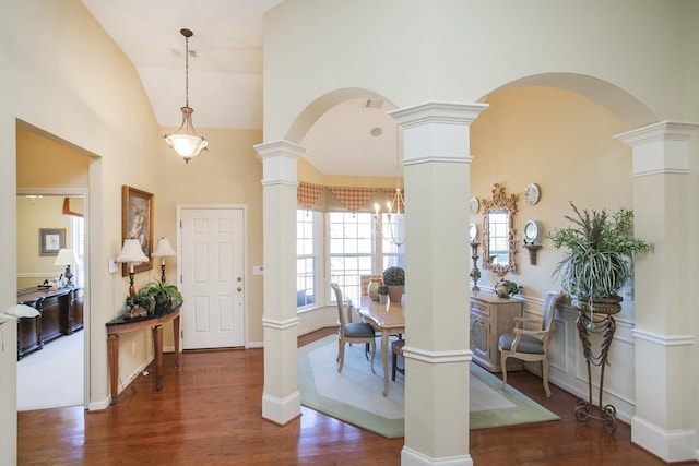 foyer featuring arched walkways, high vaulted ceiling, wood finished floors, baseboards, and ornate columns