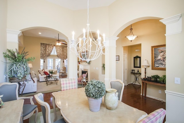 dining room featuring a ceiling fan, arched walkways, decorative columns, and wood finished floors