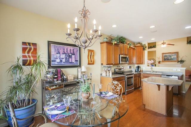 interior space featuring ceiling fan with notable chandelier, wood finished floors, a sink, appliances with stainless steel finishes, and brown cabinetry