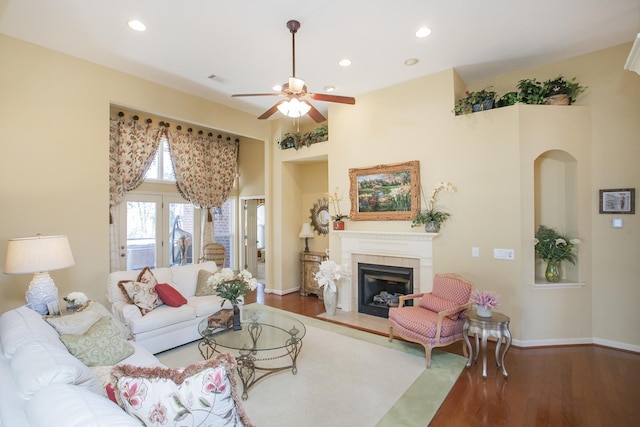 living area featuring a glass covered fireplace, recessed lighting, baseboards, and wood finished floors