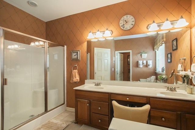 full bath featuring double vanity, a shower stall, a sink, and tile patterned floors