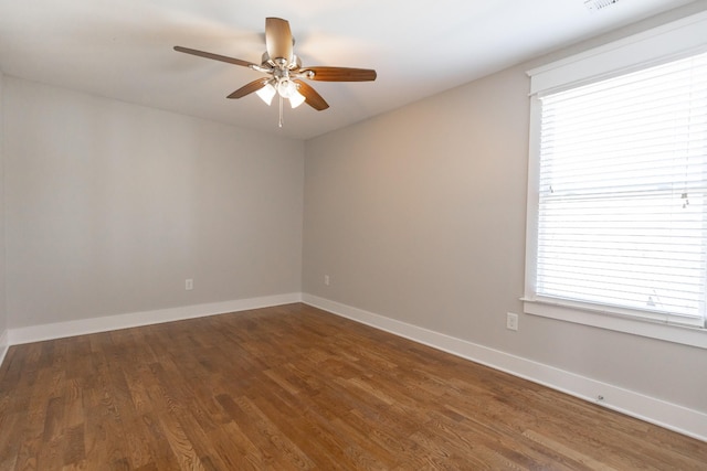 spare room featuring ceiling fan, plenty of natural light, wood finished floors, and baseboards