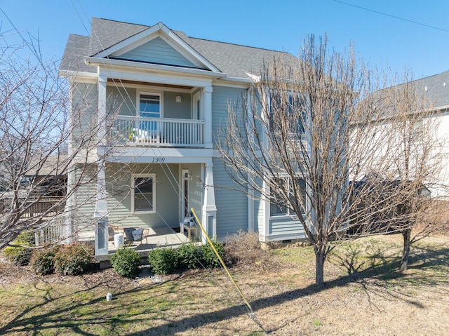 view of front facade featuring a shingled roof, crawl space, covered porch, and a balcony