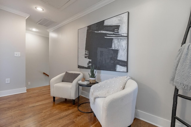 living area featuring attic access, visible vents, ornamental molding, wood finished floors, and an upstairs landing