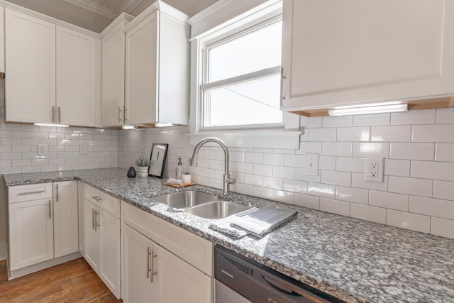 kitchen with light stone counters, tasteful backsplash, white cabinets, a sink, and light wood-type flooring