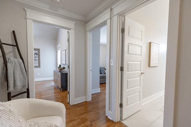 hall with ornamental molding, light wood-style floors, and baseboards