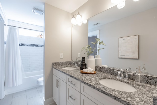 bathroom with toilet, double vanity, a sink, and visible vents