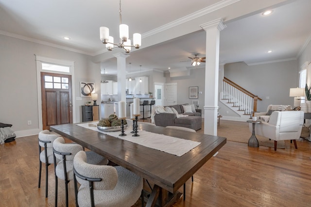 dining space with baseboards, ornamental molding, wood finished floors, stairs, and ornate columns