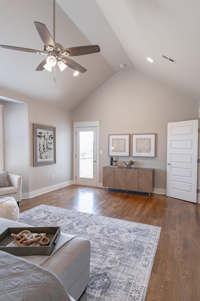 living room featuring lofted ceiling, visible vents, ceiling fan, wood finished floors, and baseboards