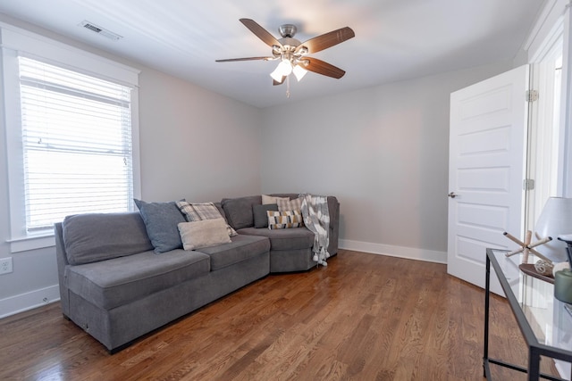 living room featuring baseboards, visible vents, ceiling fan, and wood finished floors