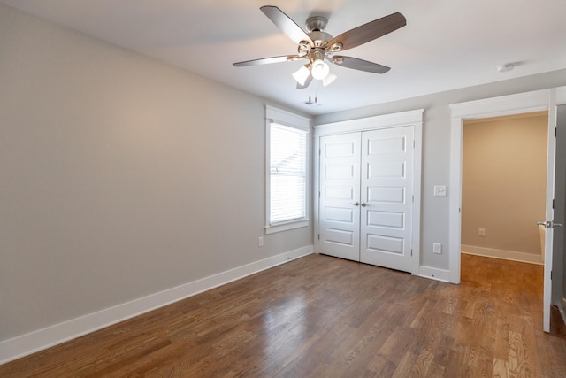 unfurnished bedroom with a closet, dark wood-style flooring, baseboards, and a ceiling fan