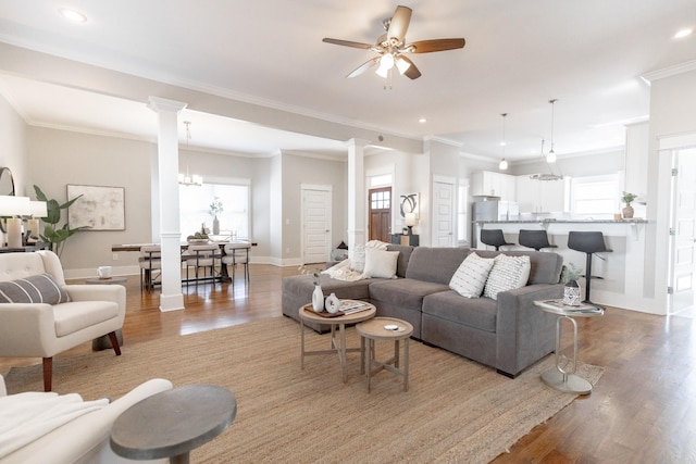 living area featuring decorative columns, baseboards, a wealth of natural light, and wood finished floors